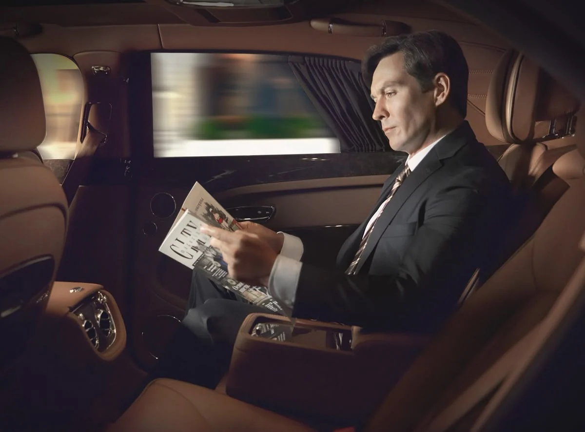 Business traveller seated in the darkened rear cabin of a Blackdoor Limo