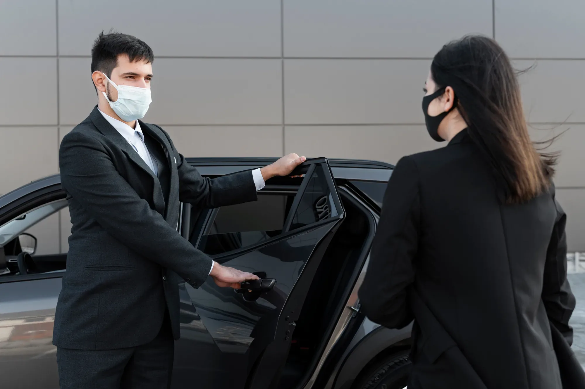 Chauffeur opening a car door for a client at the kerbside